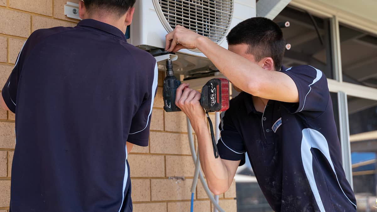 technician drilling air conditioner onto bracket