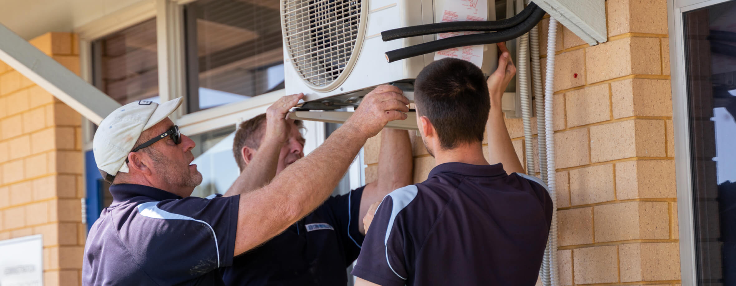 commercial air conditioner technician hanging up outdoor air conditioner unit