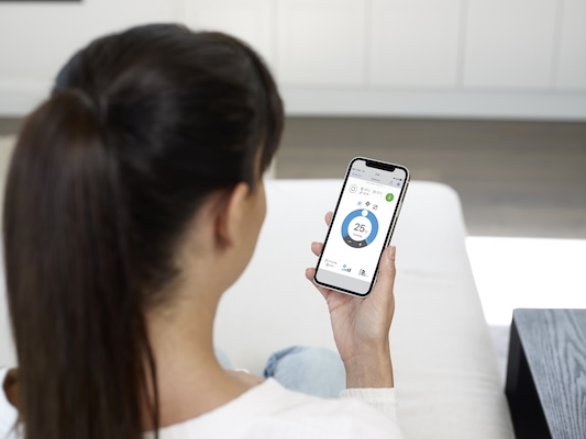 lady with smart split system remote on phone